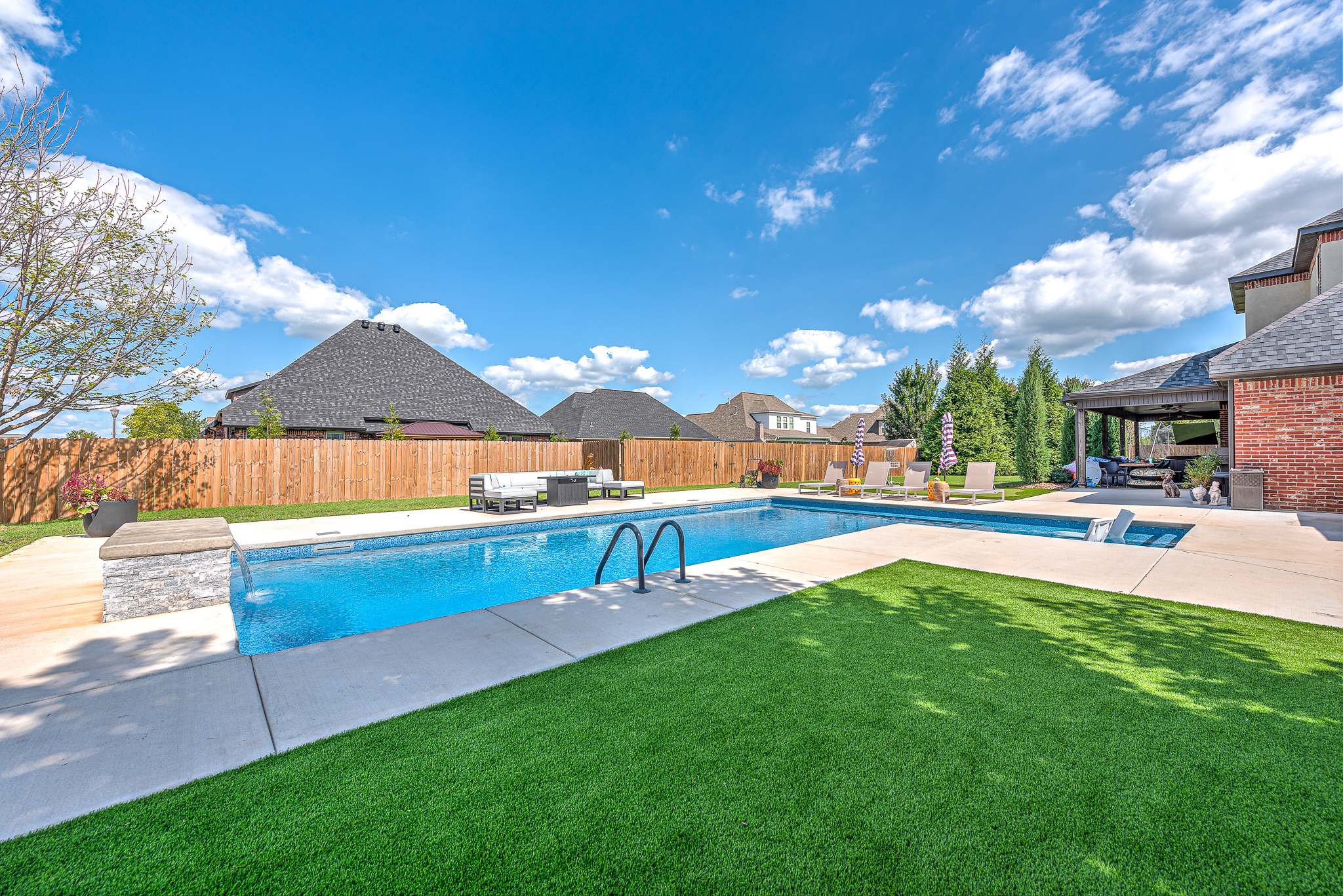Custom pool with tanning ledge and water feature in NWA backyard