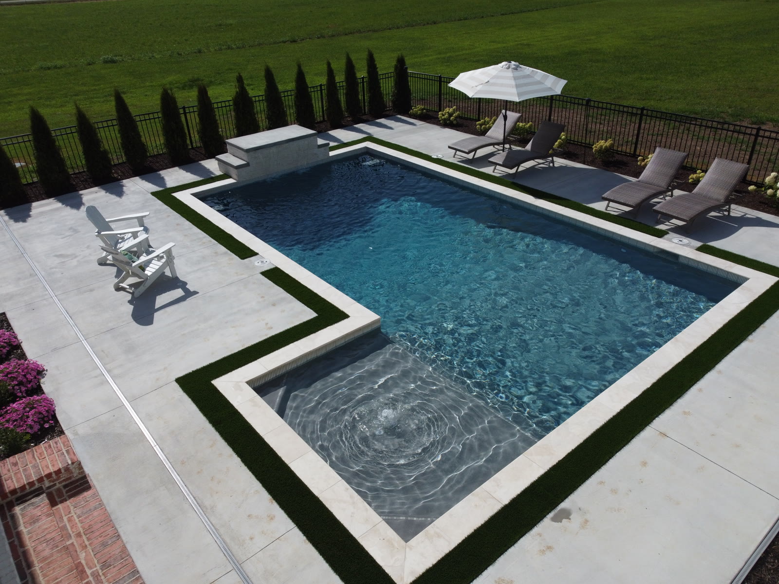Custom inground pool with spa, tanning ledge and premium hardscape by Saltscapes NWA