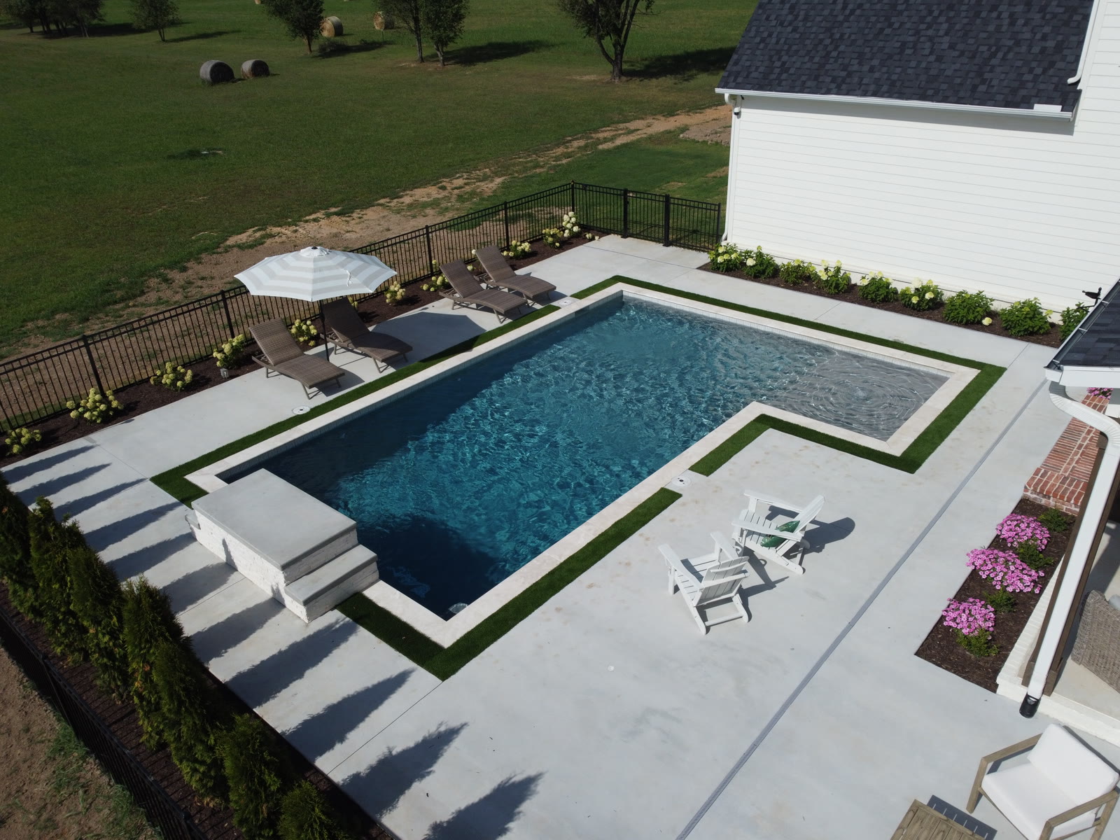 Drone view of luxury custom pool and backyard with rural Northwest Arkansas backdrop